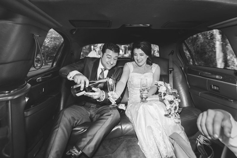 bride and groom drinking champagne in a limousine