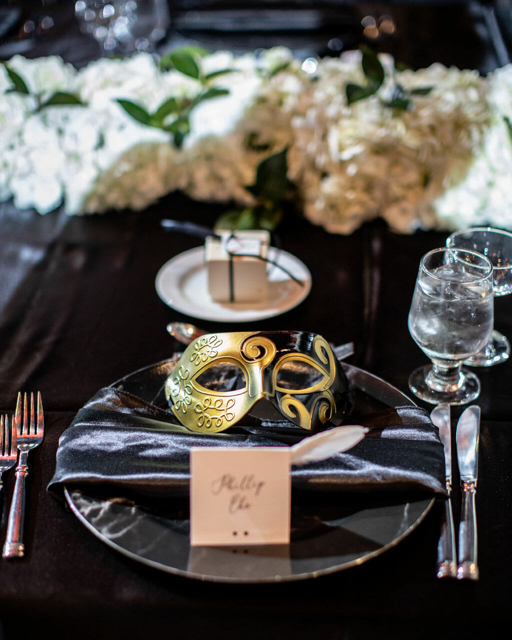 mardi gras themed wedding reception table setup with gold mask and black linen