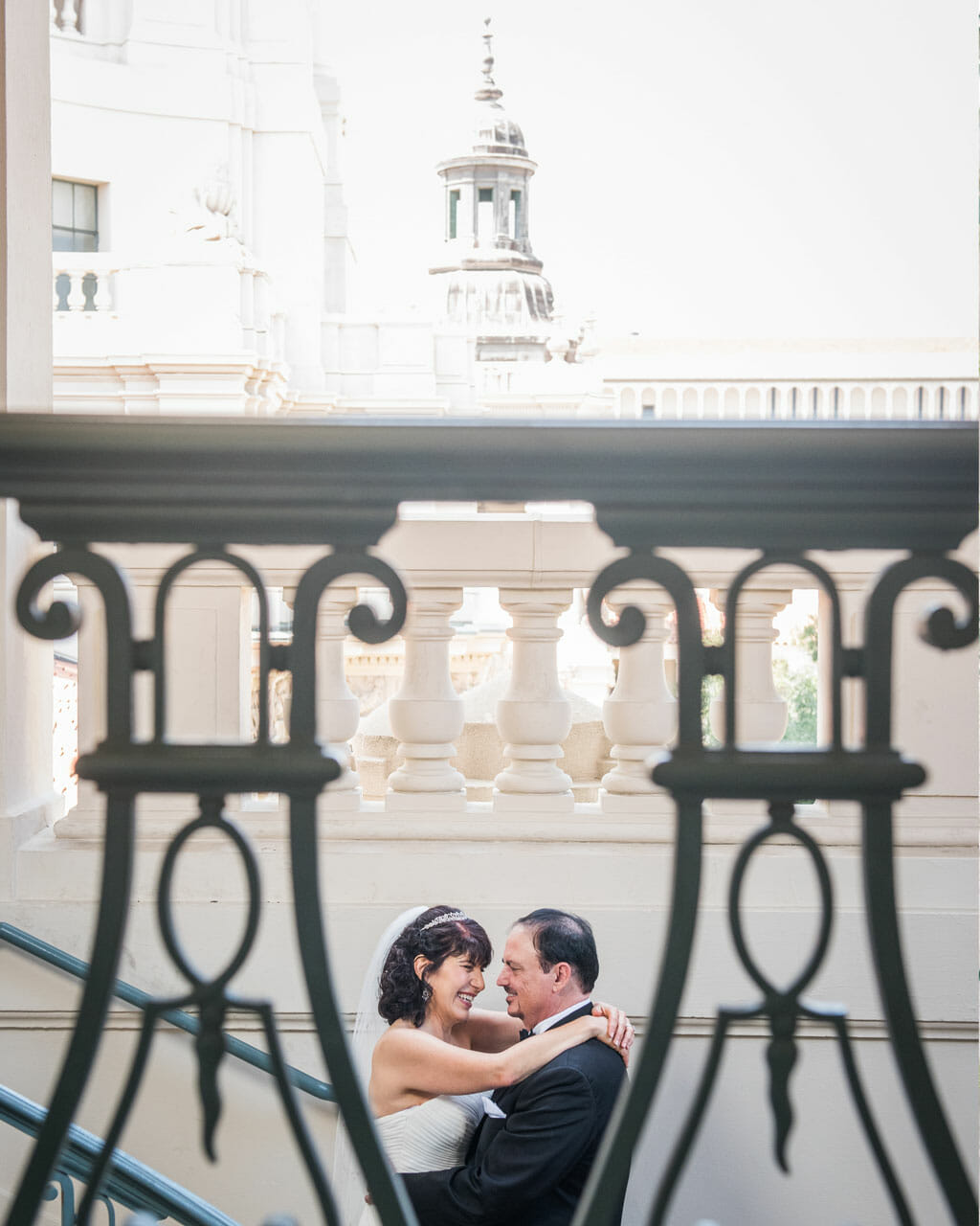 wedding couple smiling and embracing in front of pasadena city hall