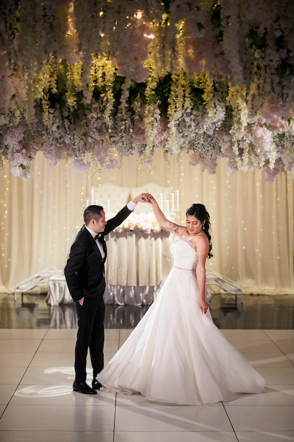 bride and groom dance under a wedding flower hanging ceiling