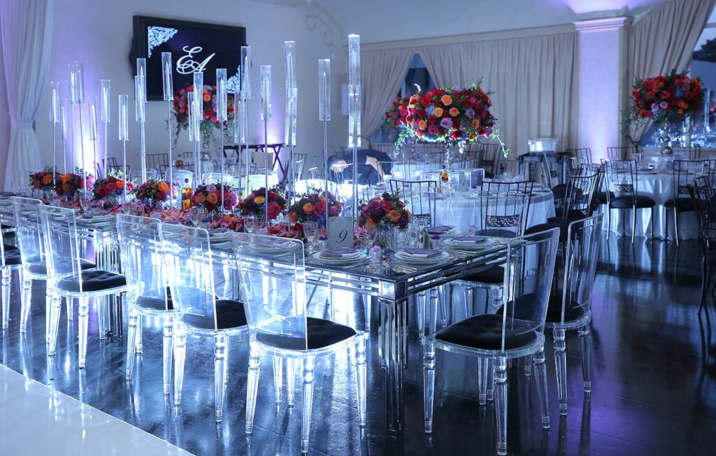 mirrored and perspex wedding receptioin table setup with red pink and orange floral centerpieces