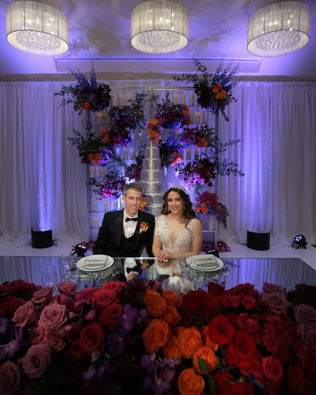 sweetheart table covered in flowers with bride and groom kissing