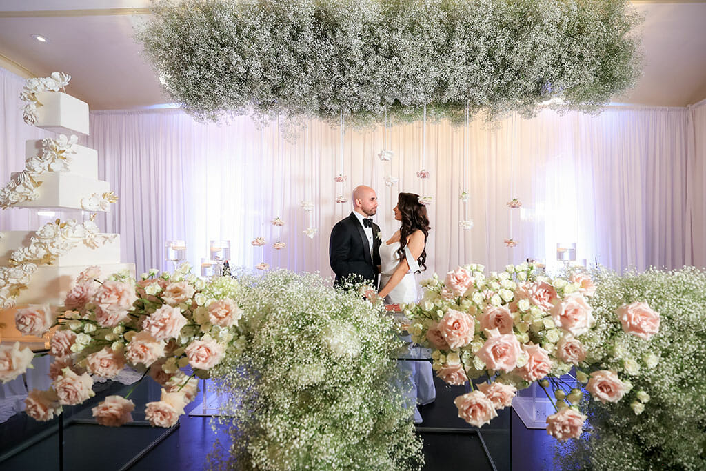 noor-banquet hall-los angeles-wedding reception-setup with pastel flowers and bride and groom standing by sweetheart table