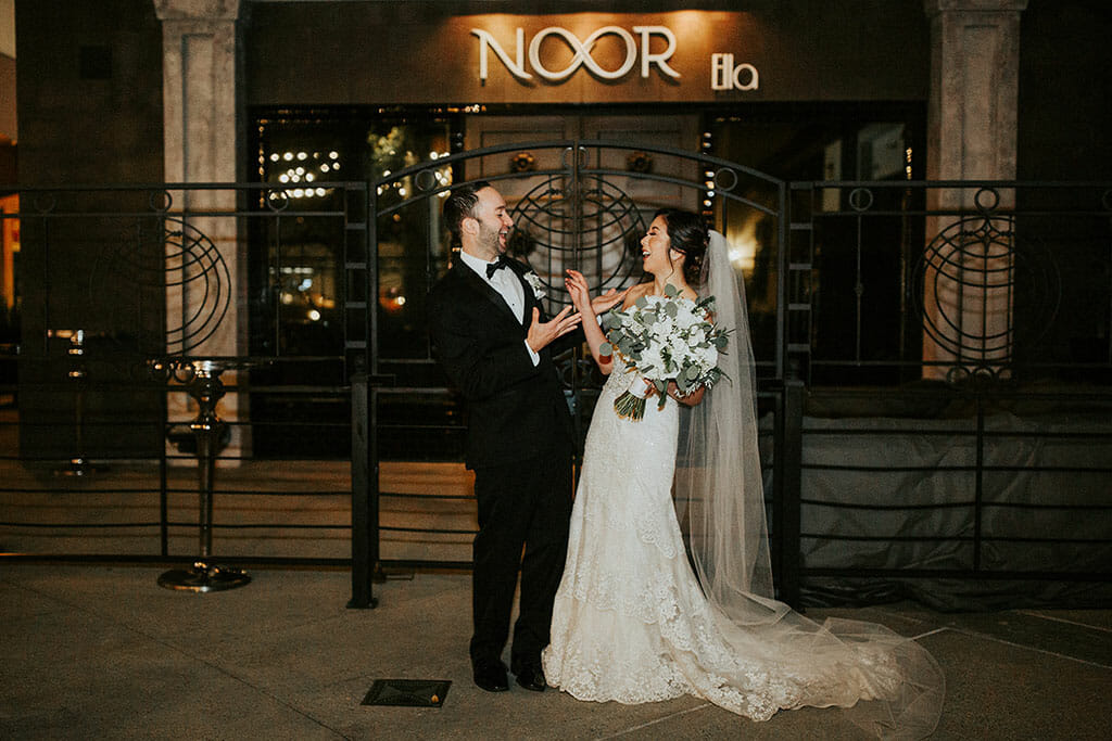 NOOR wedding couple laughing and posing outside of the ella ballroom and banquet hall at night with romantic lighting