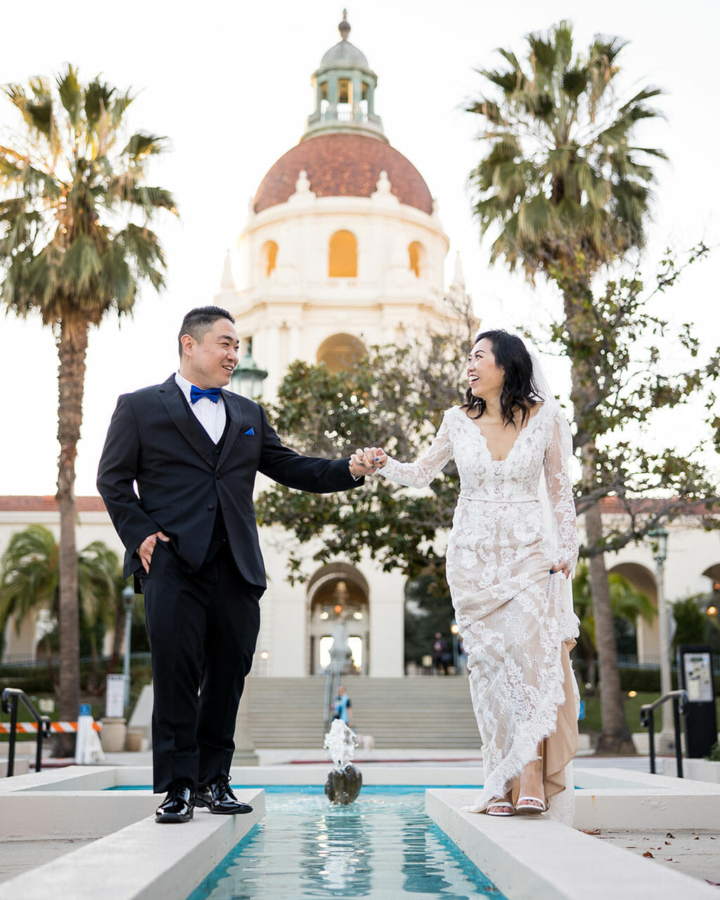 NOOR los angeles wedding couple holding hands with the pasadena city hall in the background