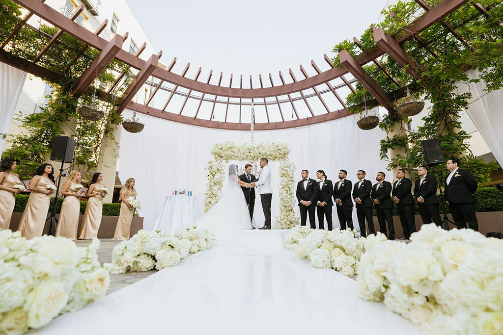 NOOR los angeles couple saying vows under a floral arch on the NOOR terrace outdoor wedding ceremony