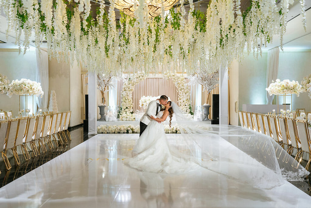NOOR wedding couple kissing undeer hanging floral ceiling in the sofia banquet hall los angeles