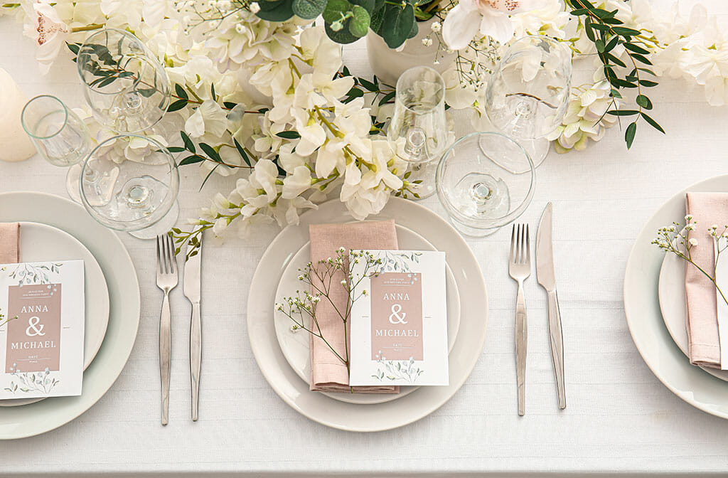 wedding table set with cream orchid centerpiece with white plates and blush linen and menus
