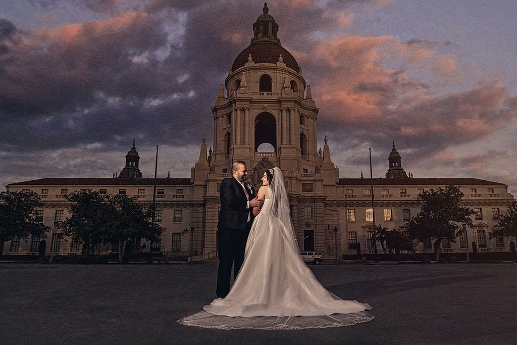 wedding couple outside pasadena city hall under a dramatic sunset sky