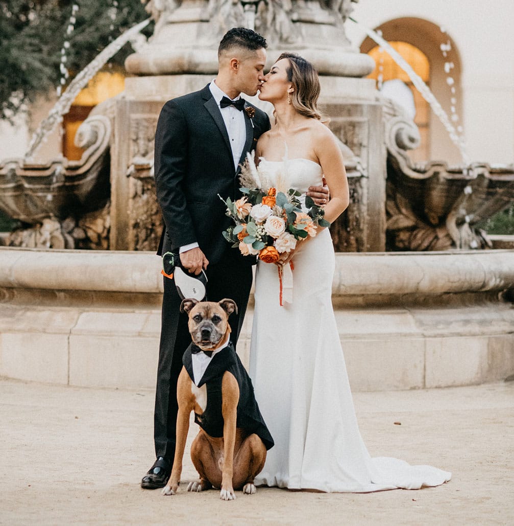 bride and groom kissing in front of pasadena city hall with their dog