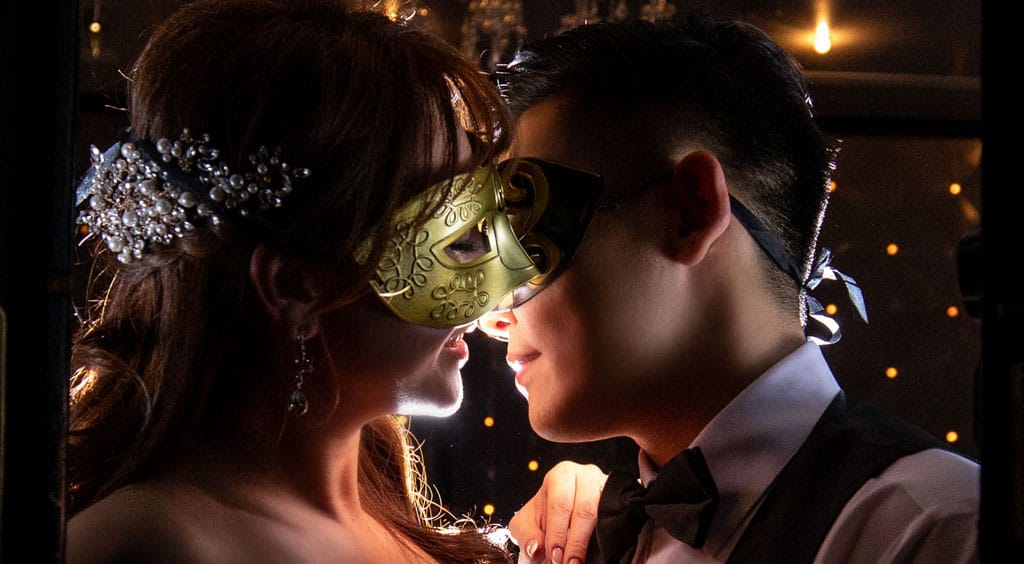 bride and groom wearing masks kiss at the entrance to the ella ballroom at noor pasadena